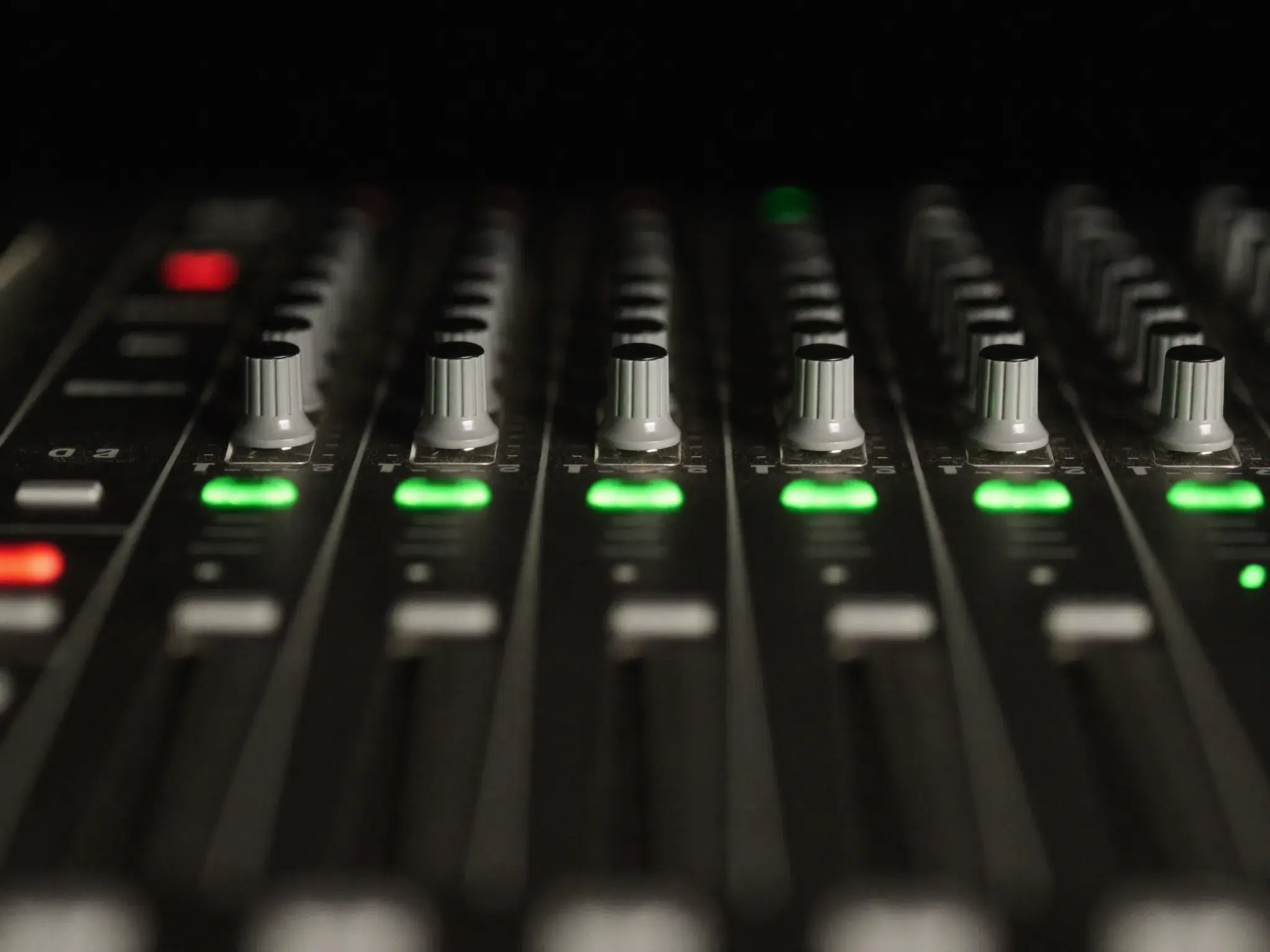 Close-up of mixing console faders glowing green in the 1331 Recordz control room