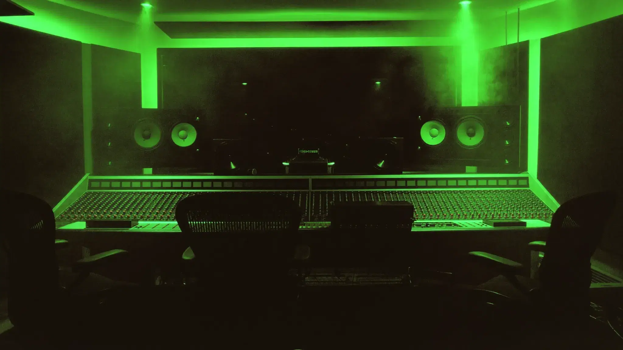 1331 Recordz control room lit in neon green, mixing console and studio monitors